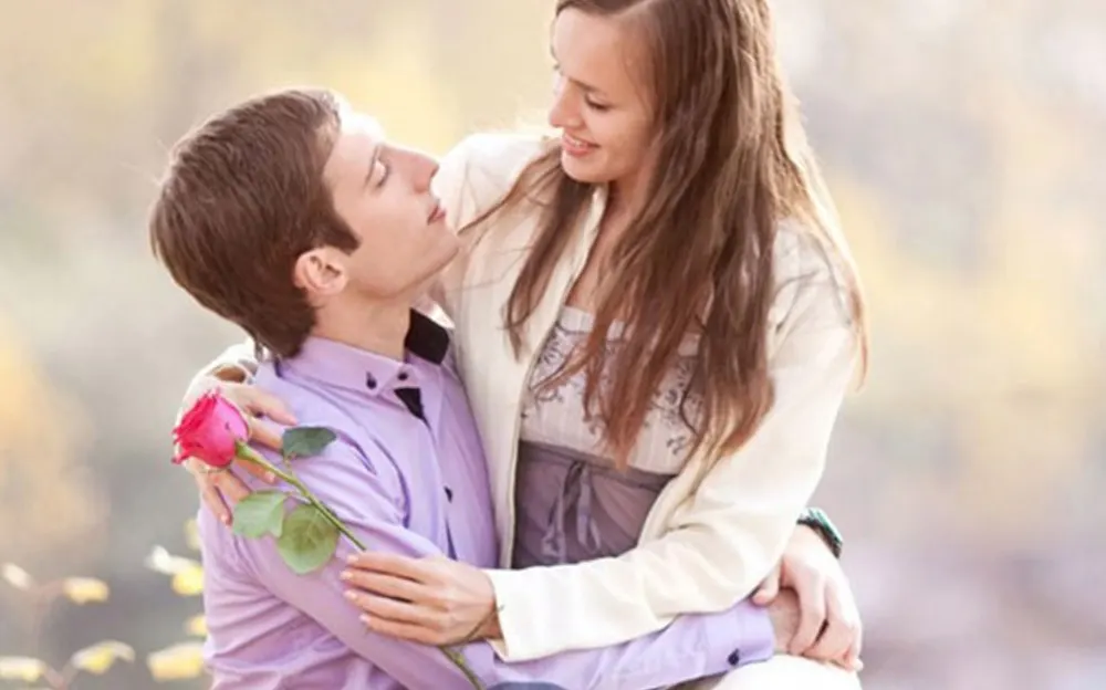 Romantic couple sharing an intimate moment outdoors, with the woman resting her hand on the man's shoulder